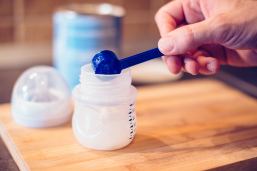 Father making baby formula in milk bottle